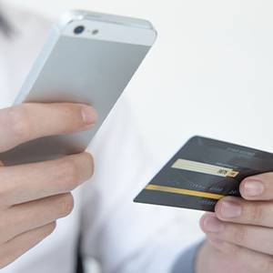 Imagem de uma pessoa segurando um celular e um cartão de crédito, simbolizando a cautela ao realizar transações financeiras e a importância de entender o Empréstimo Consignado CLT.