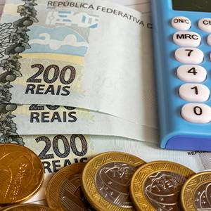 Imagem de dinheiro, moedas e uma calculadora, representando os cálculos e a organização financeira necessários ao solicitar um Empréstimo Consignado CLT.