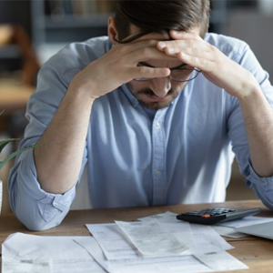 Homem preocupado diante de contas e calculadora, refletindo o impacto do capital de giro mal administrado nas finanças empresariais.