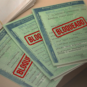 Documentos de veículos com carimbo de bloqueado, ilustrando situação de bloqueio relacionada à Busca e apreensão.