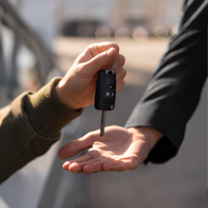 Pessoa entrega a chave do carro para agente de terno, representando a devolução do veículo em cumprimento de busca e apreensão.